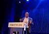 Mann taler fra en scene med skiltet «MARITIM UKE» foran en blå, mønstret bakgrunn.