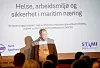 Morten Kveim står på en scene foran en presentasjon om helse og sikkerhet i maritim næring.