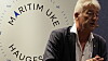 Gråhåret mann i mørk jakke taler foran en vegg med teksten Maritim Haugesund.