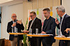 Fire menn deltar i en panelsamtale ved et bord med mikrofoner og vannglass i et møterom.