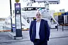 Ronny Øksnes står ved en fergeterminal med en passasjerferge og terminalutstyr i bakgrunnen.