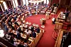 Oversiktsbilde av Stortingssalen med representanter på plass rundt det røde gulvet.