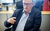 Hans Sande sitter i en stol på et kontor og gestikulerer under en samtale.